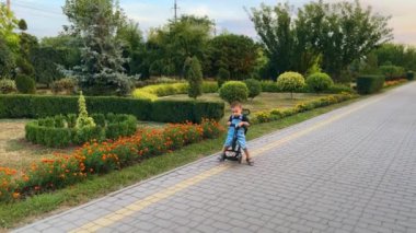 Güzel bir parkta bisiklet süren beyaz bir oğlan çocuğu. Yazın dışarıda tatlı bir çocuk..