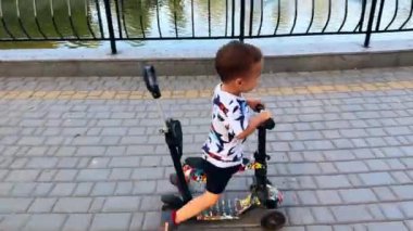 Dışarıda bisiklete binen sevimli gülümseyen bebek. Şirin çocuk göletin yakınındaki parkta. Üst görünüm.