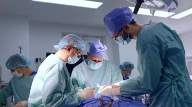 Nöroşirürji ameliyatı erkek cerrahlardan oluşan bir ekip tarafından gerçekleştirildi. Sıhhiyeciler hastanın etrafında durup iş birliği yapıyorlar..