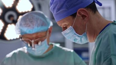 Maskeli bir doktorun konsantre yüzü. Yan görünüş yakın. Cihaz gözlüklü yetişkin cerrah arka planda çalışır..