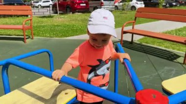 Atlıkarıncada şapkalı sevimli beyaz bir çocuk. Yazın çocuk parkında gülümseyen sevimli çocuk..