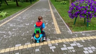 Gülümseyen güzel bir çocuk oyuncak arabaya neşeyle biniyor. Mutlu çocuk sonbaharda yürüyüşe çıkar..