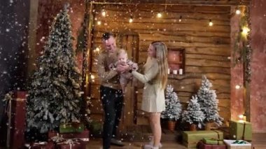 Sevgi dolu ebeveynler el sallar ve sevimli küçük oğullarını öperler. Güzel beyaz bir aile Noel tatilini birlikte geçiriyor..