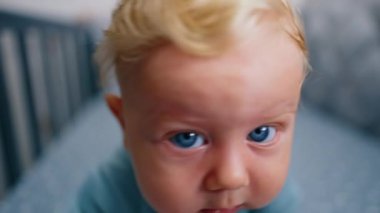 Büyük mavi gözlü, sevimli, beyaz, sarışın bir bebeğin yüzü. Bebek kamerayı almaya çalışıyor ve ağlamaya başlıyor. Kapat..