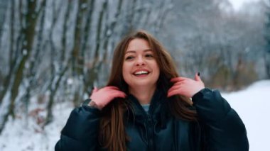 Esmer kadın kışın dışarıda eğleniyor. Bayan uzun siyah saçlarını sallıyor ve mutlu bir şekilde gülümsüyor. Bulanık arkaplan.