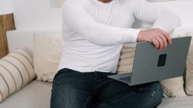Beyaz gömlek giyen beyaz erkek dizüstü bilgisayarını açıyor. Evden, ofisten uzakta çalışıyor..