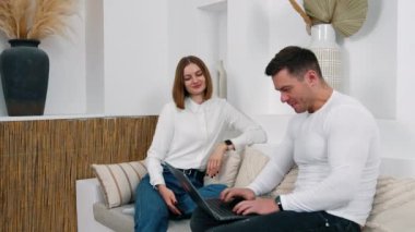 Erkek ve kadın kanepede rahatça otururlar. Erkek, dizüstü bilgisayarla çalışmaya başlar ama bilgisayarını hemen kapatır. Bayan akıllı telefonunu tutuyor..