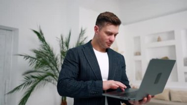 İşadamı dizüstü bilgisayarda yazar, aleti kapatır ve kameraya bakar. Kendine güvenen ceketli bir adamın portresini yakından çek..