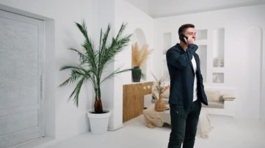 Ceketli sportif Kafkasyalı adam açık modern odada telefonda konuşuyor. İş görüşmesi, müşterilerle ya da ortaklarla konuşmak.