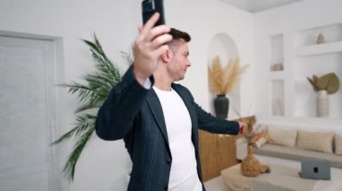 Atletik beyaz adam video konuşması yapıyor. Adam arkasında bir şeyi işaret eder ve yana döner..