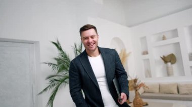 Elinde dizüstü bilgisayar tutan mutlu, beyaz bir adam. İşadamı bilgisayarını açar ve daktilo eder..