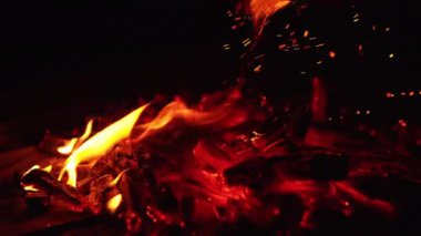 Kamp ateşinin için için için için için için yanan közleri bir sopayla hareket ettiriyor. Güzel kıvılcımlar karanlığa yükselir. Kapat..