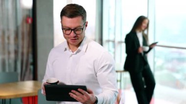 Geniş ofiste kahve molası. Erkek ve kadın ayrı odada aletlerle durup içki içiyorlar..