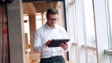 Adam stil kalem kullanarak dizüstü bilgisayarına odaklanmış. Bayan meslektaşım geldi, gözlük taktı ve alet ekranına baktı..