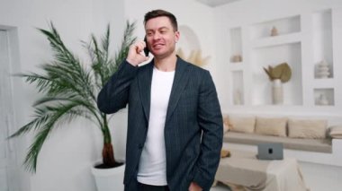 Ceketli bir adam telefonda konuşuyor ve gülüyor. Müşterilerle iletişim kuran iş adamı.