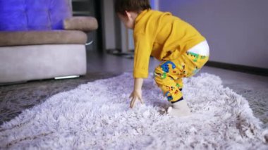 Neşeli enerjik erkek bebek etrafında dönüyor. Sevimli çocuk evde eğleniyor..