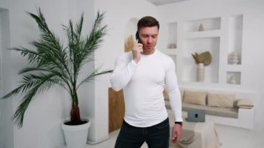 İş adamı telefonda iş meselelerini çözüyor. Beyaz gömlekli adam ortaklarla ya da müşterilerle konuşuyor..