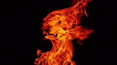 Gecenin karanlığında havada süzülen uzun ateş alevi. Tine kıvılcımları karanlıkta yanıp sönüyor.