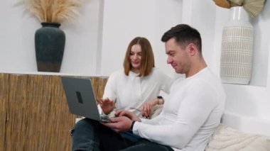 Kanepede oturup dizüstü bilgisayara bakan beyaz bir çift. İnternet kumandasında çalışan insanlar.