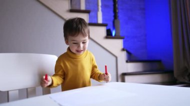 Sarı kazaklı sevimli bir bebek elinde kalem olan bir masaya gelir. Çocuk kalemi kağıdın yanına alıp komik bir şekilde hapşırıyor..