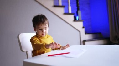 Tatlı çocuk çizimini bitirdi, kalemi bıraktı ve ayağa kalkmak istedi. Çocuk aniden durdu ve çizime geri döndü..