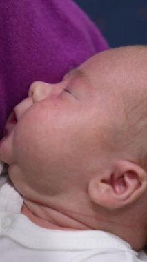 Şirin küçük bebek acıkmış ve ağzını açmaya hazır. Şefkatli anne bebeğe bir şişe verir. Bebek süt şişesini alır. Dikey video