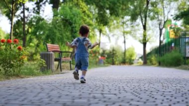 Küçük çocuk dışarıda koşuyor. Çocuk dışarıda parkta koşuyor..