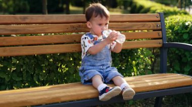 Bankta oturan küçük bir çocuk. Yaz mevsimi açık hava oyunu.