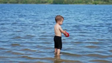 Nehir sahilinde oynayan bir çocuk. Yaz suyu göleti oyun alanı.