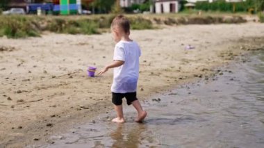 Suyun üstünde oynayan tatlı bir erkek bebek. River plajı küçük çocuğu eğleniyor..