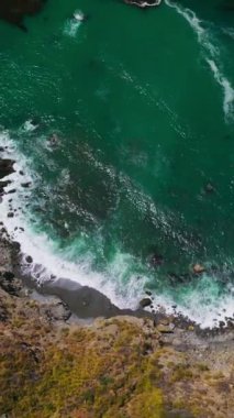 Kaliforniya, ABD 'de Pasifik Okyanusu' nun güneşli sularında parlayan güzel bir akuamarin. Rocky köpüklü dalgalarla karaya vurdu. Kuş bakışı. Dikey video
