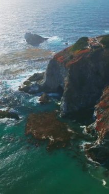 California sahil şeridindeki kayalıklarda bulunan malikâneye daha yakın uçuyorum. Pasifik Okyanusu engebeli kıyılarda dalgalar savurdu. Hava görüntüsü. Dikey video