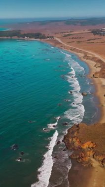 Okyanusun mavi sularıyla çevrili ıssız bir kara parçası. ABD 'nin Kaliforniya eyaletinin Morro Körfezi kıyı şeridine giden yol. Üst Manzara. Dikey video