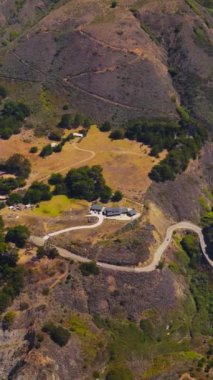 ABD 'nin Kaliforniya, Morro Körfezi' ndeki dağlık okyanus manzarasının çarpıcı manzarası. Birkaç ev ve kayalık sahil şeridinde hava manzaralı dolambaçlı otoyol. Dikey video