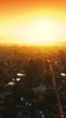 Özel kulübeleri ve boş caddeleri olan yeşil, rahat bir şehir. Dağlara ve vadiye yayılan inanılmaz batan güneş ışığı. Üst Manzara. Dikey video