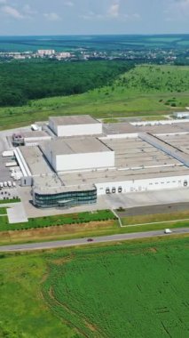 Yeşil doğanın üretim tesisi. Kırsal bölgedeki yol kenarındaki endüstriyel kompleks. Hava görüntüsü. Dikey video