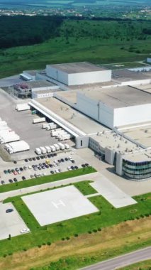 Modern endüstriyel kompleks. Doğanın arka planında büyük bir üretim tesisi var. Havadan bak. Hareket kamerasının üstünü indir. Dikey video