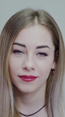 Güzel genç bir kadının portresi. Mükemmel makyajlı gülümseyen kız kameraya bakıyor. Çekici bir kadının mutlu yüzü. Yakın plan. Dikey video