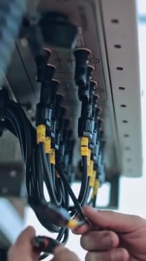 İşçi eli elektrik ekipmanını bağlar. Dışarıdaki elektrik sistemine siyah kablolar bağlayan elektrikçi. Dikey video