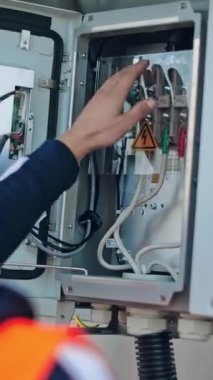 Elektrikçi elektrik kablolarını kontrol ediyor. Transformatördeki güç sistemini erkek mühendis kontrol ediyor. Dikey video