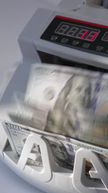 Erkek, para makinesine bir tomar Amerikan doları koyuyor. Mali işlemler için ekipman çalışıyor. Yüksek açı. Kapatın. Dikey video