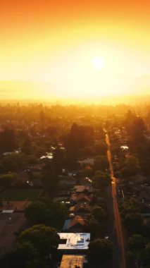 Parlak güneş ışınlarındaki güzel yeşil şehrin inanılmaz manzarası. Napa, California, ABD turuncu güneşli gökyüzünün arka planında. Üst Manzara. Dikey video