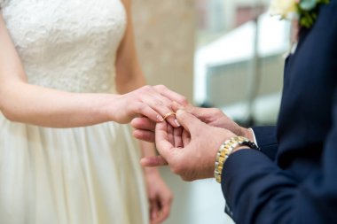 Bir damat düğün töreninde gelininin parmağına bir alyans takar..