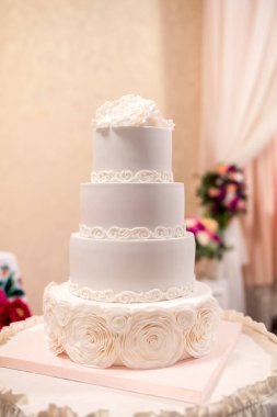 Dört katlı bir düğün pastası. Narin beyaz kremalı ve çiçekli..