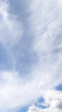 Kümülüs ve dönen bulutlar yaz gökyüzünde dönüşür. Birden fazla bulutla mavi gökyüzüne alçak açı. Zaman ayarlı. Dikey video