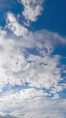 Yumuşak beyaz bulutlar farklı yönlere hareket ediyor. Spindrift bulutları parlak güneşle aydınlandı. Zaman ayarlı. Dikey video
