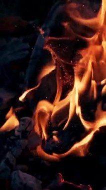 Parlak kıvılcımlı alev patlaması. Kapkara yanan kütükler, arka planda alev alev yanarak patlarlar. Yakın plan..