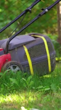 Bahçe malzemeleri. Elektrikli çim biçme makinesiyle çim biçen bir işçi. Çim biçme makinesi çalışıyor..