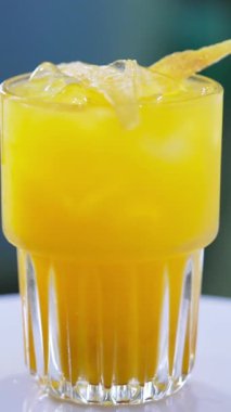 Buzlu ve cipsli portakal aromalı kokteyl. Dönen masada güzel bir içecek var. Yakın çekim. Dikey video