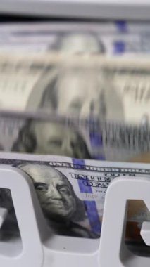 100 dolarlık tomar para sayma makinesiyle hesaplanıyor. Notlardaki Benjamin Franklin portresi. Yakın plan. Dikey video